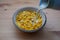 Cornflakes cereal in a ceramic bowl with milk being added