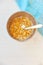 Cornflakes in a metal bowl with milk on a painted white wooden background. Composition with a dish towel and spoon.