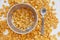 Cornflakes in a metal bowl with milk on a painted white wooden background. Cornflakes scattered on a wooden table with