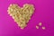 Cornflakes on a pink background in the form of a heart