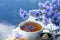 Cornflower herbal tea in white cup on white crochet napkin on table outdoors, healthy cornflower drink