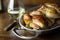 Cornish hens in an aluminum baking pan right out of the oven, shown with stemless glass of white wine and vintage fork.