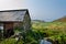 Cornwall / United Kingdom- 26 August 2013: A stone barn with slate roof next to a small stream of water overlooking a scenic grass