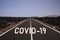 Corona virus uncertain bleak perspective symbol concept: Endless road through desert with word covid-19
