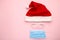 Coronavirus Christmas santa hat with protective mask and glasses on pink. Covid-19 Christmas