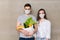 Coronavirus concept with couple, young man and woman in medical mask with food bag, fruits and vegetables