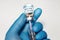 Coronavirus conceptual image of doctor hand in surgical glove holding a vaccine bottle with injection syringe in close up view