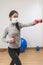 Coronavirus. COVID-19. Young beautiful woman doing sport at home during quarantine with mask protection. Stay at home workout