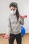 Coronavirus. COVID-19. Young beautiful woman doing sport at home during quarantine with mask protection. Stay at home workout