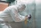 Coronavirus infection. Paramedic in protective mask and costume disinfecting an elevator with sprayer,