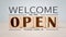 After a coronavirus lockdown quarantine, welcome we\\\'re open vintage black retro sign on a wood blog for a cafe.