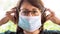 Coronavirus outbreak: A middle-aged woman putting on a medical disposable mask to avoid contagious viruses