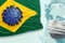 Coronavirus over brazilian flag and the BRL banknotes face wearing a mask