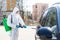 Coronavirus Pandemic. Disinfector in a protective suit and mask sprays disinfectants of car outdoors