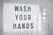 Coronavirus pandemic and hand hygiene concept - light box with wash your hands message and bottles of sanitizer or liquid soap