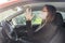 Coronavirus. A police medical technician in full protective gear collects a sample from a young woman sitting inside her car. Coro