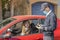 Coronavirus. A police medical technician in full protective gear collects a sample from a young woman sitting inside her car. Coro