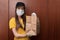 Coronavirus and quarantine. Safe food delivery from restaurants. Young woman courier in uniform in a medical antibacterial mask