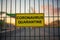 Coronavirus Quarantine sign on a fence with blured city view on a background at sunset