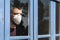 Coronavirus. Sick man of corona virus  looking through the window and wearing mask protection and recovery from the illness in hom