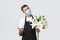 Coronavirus, social distancing business during covid-19 pandemic concept. Charming salesman, florist in flower shop
