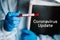 Coronavirus update text. A hands of Doctor, nurse, scientist in a protective suit hold a test tube with biological sample. SARS-