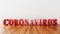 Coronavirus word made of big red letters on wooden floor