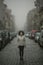 Coronovirus. Multicultural asian woman in antiviral mask stands in street in cloudy weather