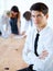 Corporate Confidence. Portrait of a handsome businessman sitting on a desk with his arms folded - blurred colleagues in