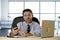 Corporate portrait of happy successful businessman in shirt and tie smiling at computer desk with mobile phone