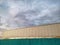 Corrugated Fence and Wall Outside Warehouse Against Cloudy Sky