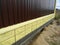 Corrugated metal panel fence installation on the brick foundation in a trench with a level line string set up