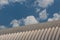 Corrugated metal ribbed quonset hut style steel building against a blue sky with clouds