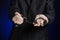 Corruption and bribery theme: businessman in a black suit with handcuffs on his hands on a dark blue background in studio isolated