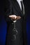 Corruption and bribery theme: businessman in a black suit with handcuffs on his hands on a dark blue background in studio isolated