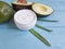 Cosmetic avocado cream product ingredient protection on a wooden hand background