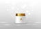 Cosmetic bottle for cream. White jar and gold glossy lid on the gray background for ads.