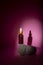 Cosmetic bottle with a pipette stands on a gray stone on a pink background. Directional light falls on the jar