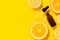 Cosmetic bottle product serum vitamin C with orange and lemon flat lay on yellow background clean water splashing
