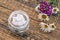 Cosmetic cream, fresh chamomile and verbena flowers on wooden background