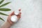 Cosmetic cream jars in hand. Woman holding white container with moisturizer marble background with copy space, defocused tropical