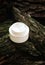 Cosmetic cream on tree bark. Organic cosmetology botanical concept. White plastic container with natural moisturizing balm