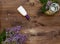 Cosmetic flat lay with a bouquet flowers lilac.Bottle cream and tea candle with birdcage on wooden slice on wooden background