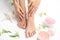 Cosmetic, flowers and woman touching her smooth feet on white towel, closeup.