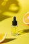 Cosmetic hyaluronic acid or hydrating oil and orange essence on yellow. Close up. Anti-cellulit care.