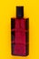 Cosmetic labels. Close-up of a red elegant male parfum glass bottle over yellow background. Copy space for your own label. Macro.