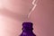 Cosmetic or medical purple bottle with pipette on a pink background. Concept of rejuvenation, treatment and care