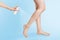 A cosmetic or medicinal product is sprayed on beautiful woman`s legs. Copy space. Light blue background. Foot health and beauty