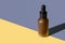 Cosmetic oil bottle with black pipette cap on double diagonal background. Mockup, poster, banner, copy space. Brown frosted vial