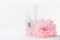 Cosmetic and perfume bottles with pink pale flower on white background, front view. Beauty and skin care